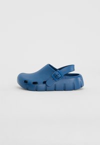 Blå gummistövlar med slingback-rem, med sidoventiler och en texturerad sula. Enkel design med en slät finish och justerbar spänne.