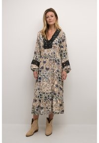 Robe longue à motifs floraux comprenant des motifs complexes en bleu et vert sur un fond crème, accentuée par un col en dentelle noire et des manches.