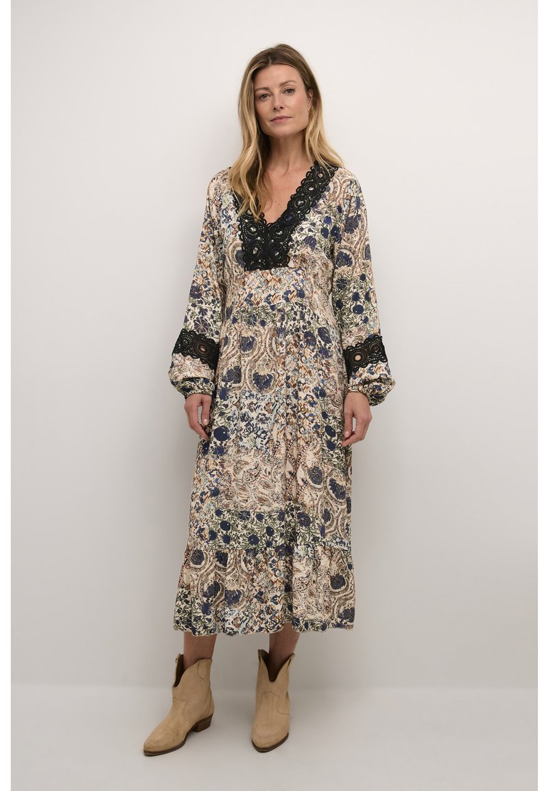 Robe longue à motifs floraux comprenant des motifs complexes en bleu et vert sur un fond crème, accentuée par un col en dentelle noire et des manches.