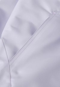 Světle fialová tkanina s hladkou strukturou, s diagonálními švy. Švy jsou pečlivě zakončeny, což zdůrazňuje kvalitu textilie.