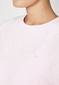 Απαλή ροζ φούτερ με ραφές, στρογγυλή rib κ neckline και κεντητό λευκό λογότυπο καρδιάς στο στήθος.