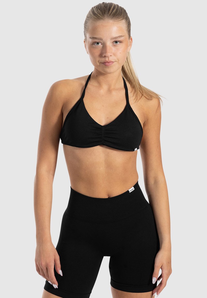 Zwart bikini-top met plooien en halternek ontwerp, gecombineerd met hoge zwarte shorts. Beide gemaakt van een gladde, rekbare stof.