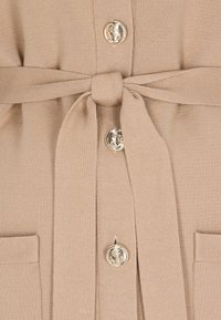 Beżowy sweter na guziki z dzianiny z pasującym paskiem związanym w supeł oraz ozdobnymi, złotymi guzikami z wytłaczanym kotwicą na przodzie.