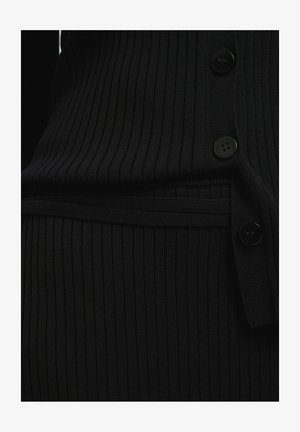 Zwarte ribgebreide kledingstuk met een knoopsluiting en een getailleerde taille. De textuur is glad met subtiele verticale lijnen en contrasterende knopen.