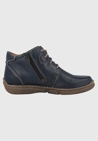 Des bottes en cuir bleu marine montantes présentent un bout arrondi, une semelle brun texturée, une fermeture éclair sur le côté et des coutures contrastantes.