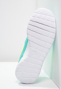 Vit sula av en Nike-sneaker med texturerat greppmönster och tygöverkänsla i turkost, placerad mot en vit hörnbakgrund.