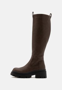 Bottes marron montantes jusqu'au genou, fabriquées en matière synthétique texturée. Elles disposent d'une épaisse semelle en caoutchouc noir et de passants en haut pour faciliter l'enfilage.