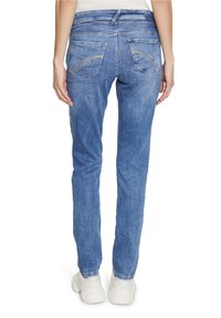 Vaqueros de mezclilla azul claro con un corte ajustado, con bolsillos traseros con costuras curvas y una textura ligeramente desgastada.