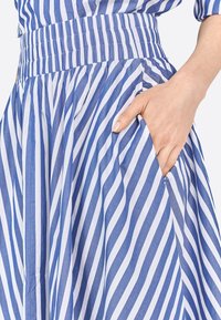 Gonna a righe blu e bianche con vita elastica e tasca laterale, realizzata in un tessuto morbido e testurizzato, dal design fluido.