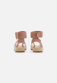 Sandali espadrilles in suede rosa con cinturini alla caviglia, suola in juta intrecciata e accentuazione in metallo dorato.