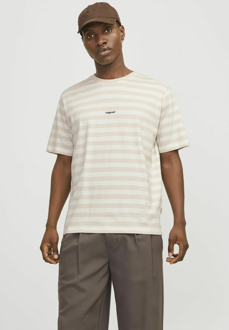 Camiseta a rayas en beige claro y crema, hecha de algodón suave. Presenta mangas cortas y un pequeño logo de "Originals" en el pecho.