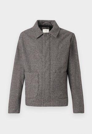 Jachetă gri în stil herringbone cu guler ascuțit, buzunare frontale și croială ajustată; prezintă un material texturat și închidere cu buton.