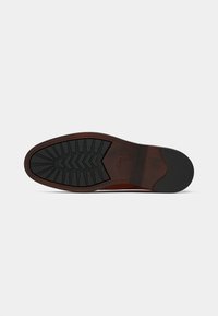 Sole of a brown leather dress shoe with black rubber tread and Clarks logo on a plain light background.
