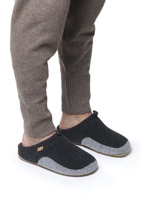 Chaussons en feutre de couleur gris foncé avec des accents gris clair. Présentent une texture douce, un design à dos ouvert, et une petite étiquette en bois sur le côté.