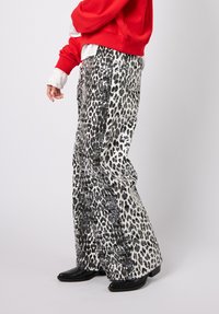 Leopardi-kuvioiset housut, joissa mustan ja valkoisen sävyissä kiiltäviä paljetteja ja mattapintaisia osia, leveälahkeinen malli ja korkea vyötärö.