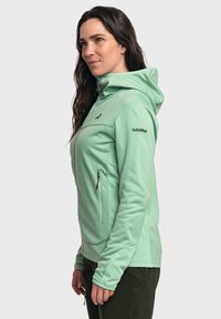 Mintgrüne Softshelljacke mit Kapuze, ausgestattet mit einer Reißverschluss-Brusttasche, taillierten Bündchen und einem dezenten strukturierten Muster.