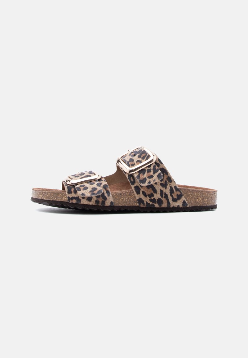 Sandale à bout ouvert avec semelle en liège, deux brides à imprimé léopard et boucles réglables dorées sur un fond blanc uni.