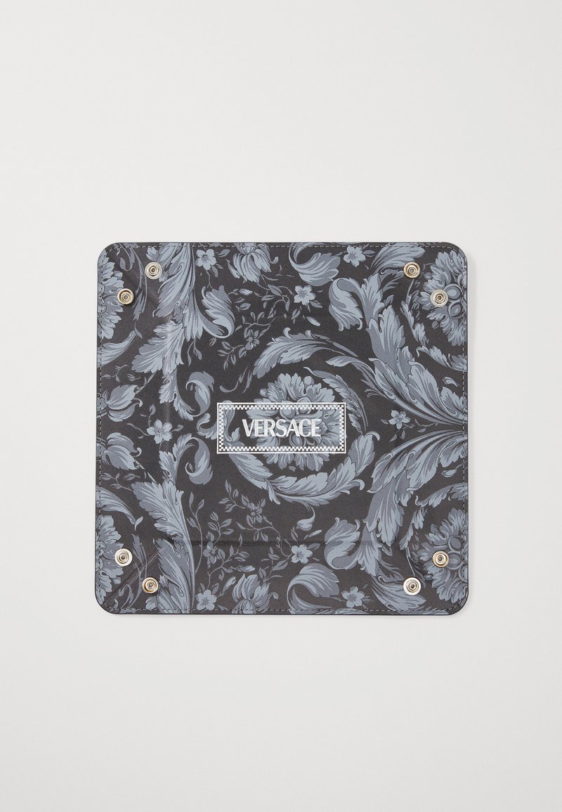 Juodas raštuotas audinys su šviesiai mėlynais gėlių ir paisley dizainais, su sidabro detalėmis ir baltu "VERSACE" etiketu centre.