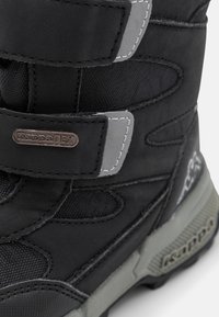 Der schwarze KappaTEX-Stiefel verfügt über ein strukturiertes Obermaterial mit grauen Akzenten, verstellbaren Riemen und einer robusten Gummisohle für Traktion und Langlebigkeit.