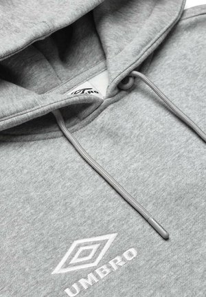 Sudadera con capucha gris hecha de una tela suave y texturizada. Cuenta con una capucha ajustable y un logo blanco bordado en el frente.