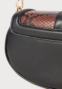 Black leather handbag with a brown and black snakeskin-patterned flap and gold hardware detail on the strap.