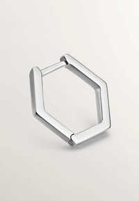 Clip de metal plateado hexagonal con bordes redondeados, superficie brillante y un diseño simple y moderno. Abertura en un lado para su función.