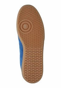 Mėlyno zomšo sneakerio padas su tekstūruotu guminiu padu, turinčiu geometrinį raštą ir apvalią logotipo detalę centre.