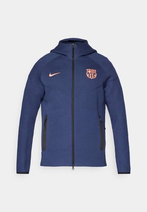 Navy blue full-zip jacket with hood, two zippered side pockets, orange Nike logo, and FC Barcelona club crest on front.
