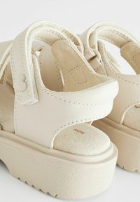 Vita, strukturerade lädersandaler med plattformssula, med justerbara remmar och mjuka fotbäddar för komfort. Hjärta-format accent på remmen.