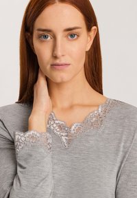 Graues Langarmoberteil mit einem gewellten Spitzenkragen und -bündchen. Glatte Textur mit Spitze in kontrastierender Farbe.