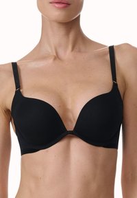 Reggiseno imbottito nero con ferretto, coppe lisce, spalline regolabili e un design minimalista. Presenta accenti di hardware discreti e nessun motivo visibile.