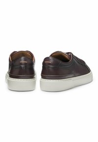 Sneaker in pelle marrone scuro con suola in gomma bianca, caratterizzate da una finitura liscia e un design minimalista con un logo discreto sul retro.