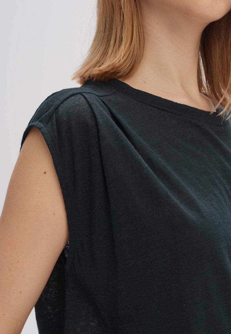 Schwarzes, kurzärmliges T-Shirt mit lockerem Schnitt, das subtile Falten an den Schultern und einen weichen, strukturierten Stoff aufweist.