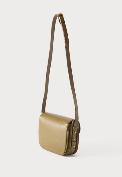 Μικρό τσαντάκι ώμου από δέρμα σε ελιάς πράσινο χρώμα με ρυθμιζόμενο ιμάντα και αγκράφα σε χρυσό χρώμα, εμφανιζόμενο σε απλό φωτεινό φόντο.