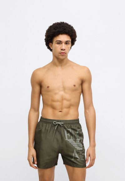 Olívazöld fürdőnadrág elasztikus derékpánttal és húzózsinórral. Jobb oldalon nagy logónyomattal. Sima, könnyű anyagból készült.