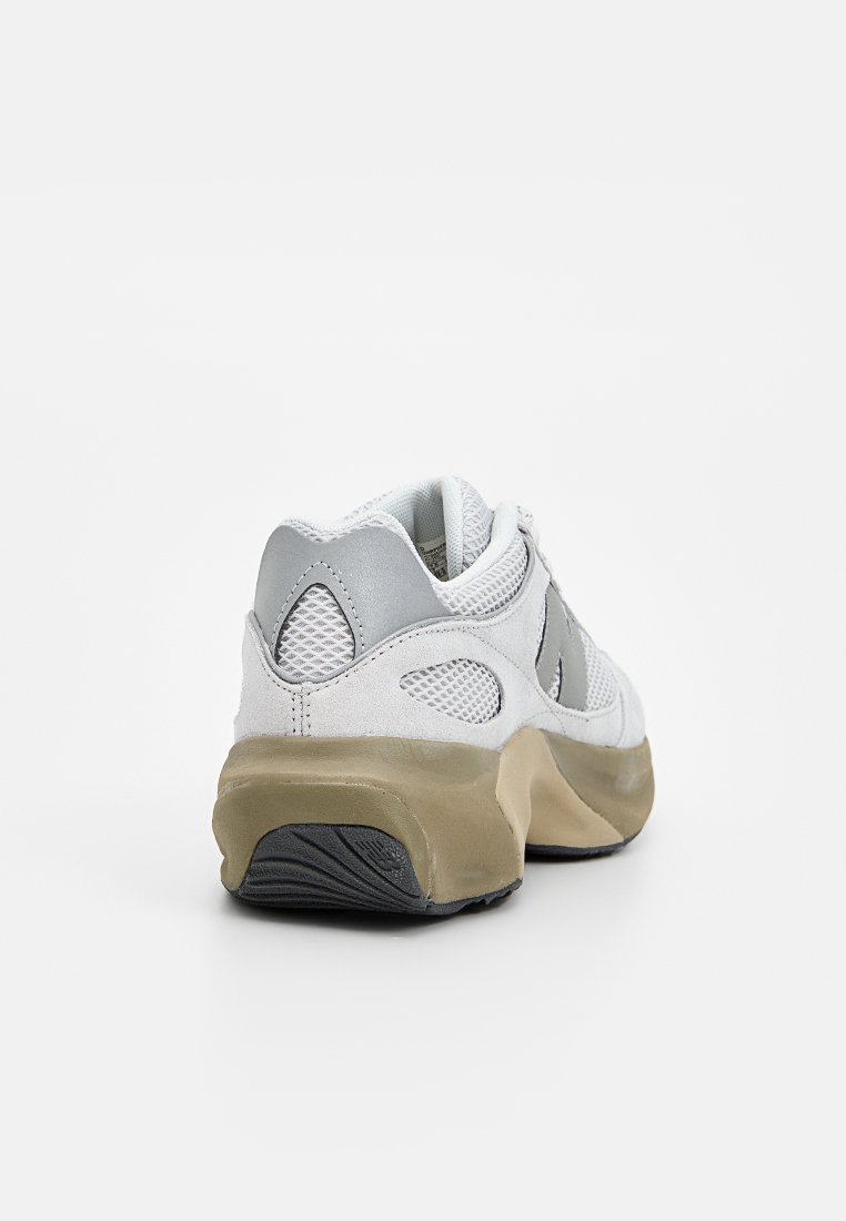 Baskets blanches avec une tige en mesh et en cuir suédé, accents gris, une semelle intermédiaire beige et une semelle extérieure en caoutchouc avec un motif texturé. Vue arrière présentée.