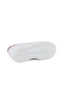 Weißer Sneaker mit einer glatten Oberfläche, roségoldenen Akzenten und einer strukturierten Gummisohle mit einem "Champion"-Logo.