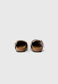 Brune korksåler sandaler med en lyserød læderoverdel, der har en justerbar spænde og åben bagdesign.