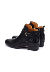 Bottines en cuir noir avec un design incurvé, un petit talon carré, des détails de boucle sur le côté et une doublure intérieure beige.