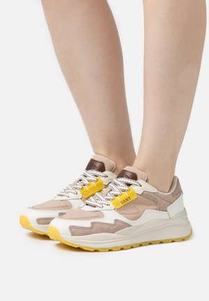 Beige and white sneakers with yellow accents, featuring a textured surface, lace-up design, and a padded collar. Rubber sole for traction.