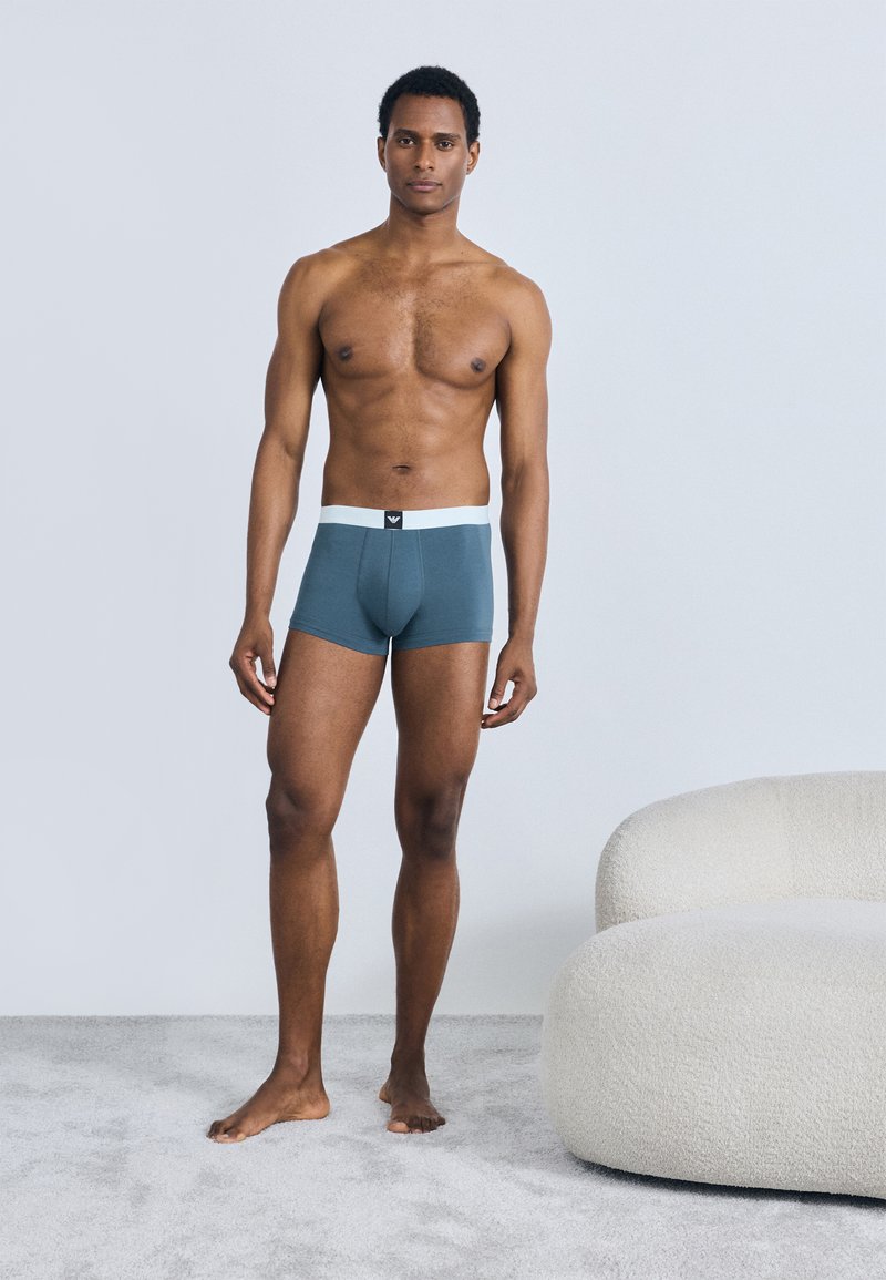 Boxers pour hommes en bleu sarcelle avec une ceinture élastique blanche. Design lisse et ajusté sans motifs ni accents visibles.