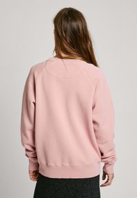 Felpa rosa realizzata in morbido misto cotone, con collo tondo, polsini e orlo a costine, maniche raglan e tessuto testurizzato.