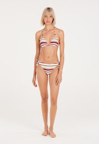 Conjunto de bikini a rayas que incluye un top triangular con bordes con volantes y braguitas con lazo a los lados. Los colores incluyen verde, rojo y blanco. Textura suave.