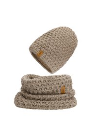 Beige gestrickte Mütze mit gerippter Textur und gewebtem Muster, kombiniert mit einem passenden Infinity-Schal, beide mit einem kleinen Lederetikett.