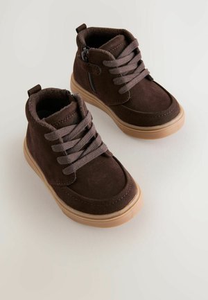 Braune Wildleder-Stiefeletten mit grauen Schnürsenkeln, Gummisohlen und einem seitlichen Reißverschluss. Weiche Innenauskleidung für Komfort. Minimalistisches Design mit Nähdetails.