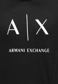 Svart bomull T-skjorte med hvit tekst: "A|X" og "ARMANI EXCHANGE" i fet, sans-serif font på forsiden.