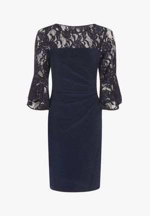 Granatowa sukienka do kolan z koronkową góra i rękawami, rozkloszowanymi koronkowymi mankietami oraz drapowanymi zdobieniami z przodu.