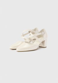 Λευκά παπούτσια από δερμάτινο βερνίκι με μυτερή μύτη, στρογγυλεμένη φτέρνα και λουράκια που διασταυρώνονται στον αστράγαλο· λείος υφή και μινιμαλιστικός σχεδιασμός.