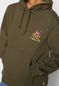 Felpa verde oliva con tasca a marsupio frontale, cappuccio con cordino e logo stampato con una corona rosa. Realizzata in tessuto morbido.