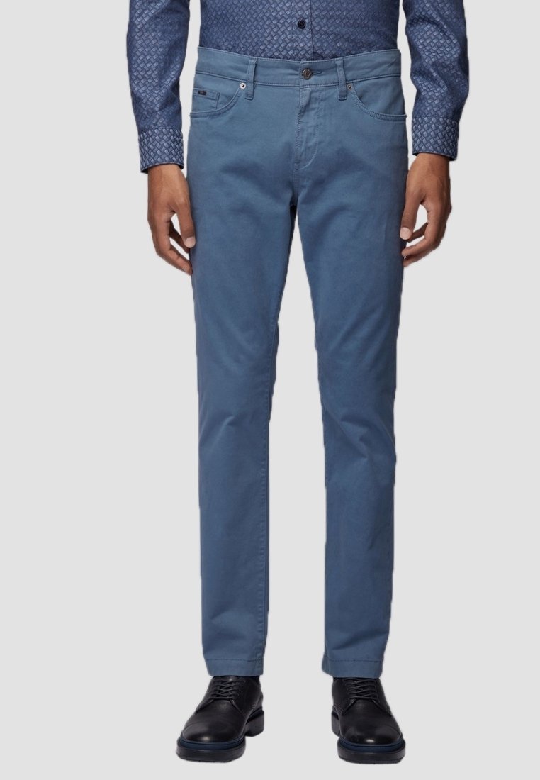 Himmelsblå bomullshosor med rak bendesign, med framfickor och dragkedja, i kombination med svarta läderskor.